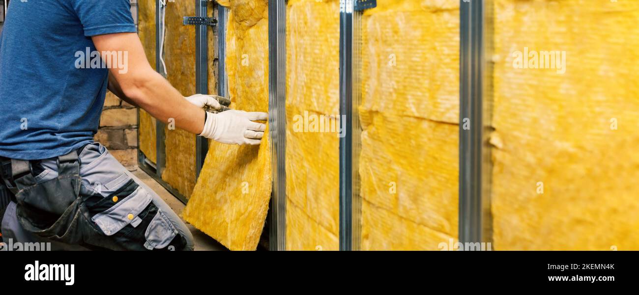 casa muro isolamento. costruzione lavoratore installare lana di vetro nel profilo di metallo telaio indoor. banner con spazio copia Foto Stock