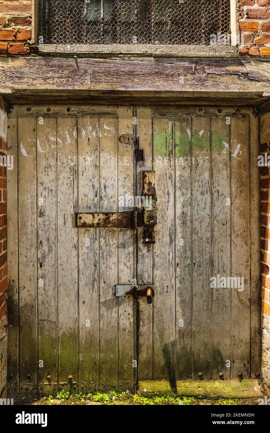 Weathered porta del magazzino della dogana di legno in Bridport, Dorset con le maniglie Rusty lucchetto e bullone Foto Stock