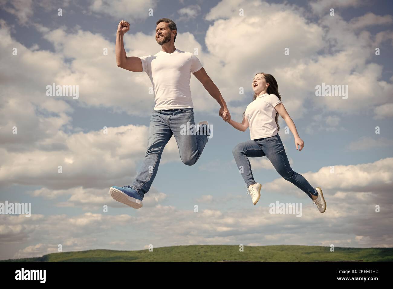 felice padre e figlia saltano in cielo. amicizia Foto Stock