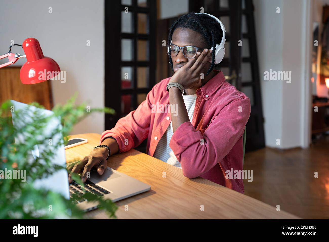Concentrato perplesso uomo afroamericano procrastinazione o fare lavoro monotono al computer portatile Foto Stock