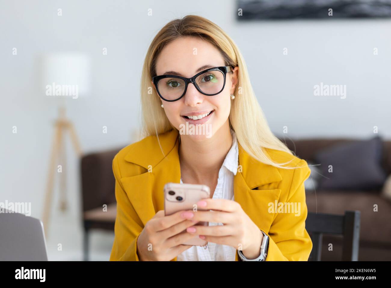 Ritratto di donna sorridente fidata dirigente seduto in un ufficio moderno, lavorare con il telefono cellulare Foto Stock