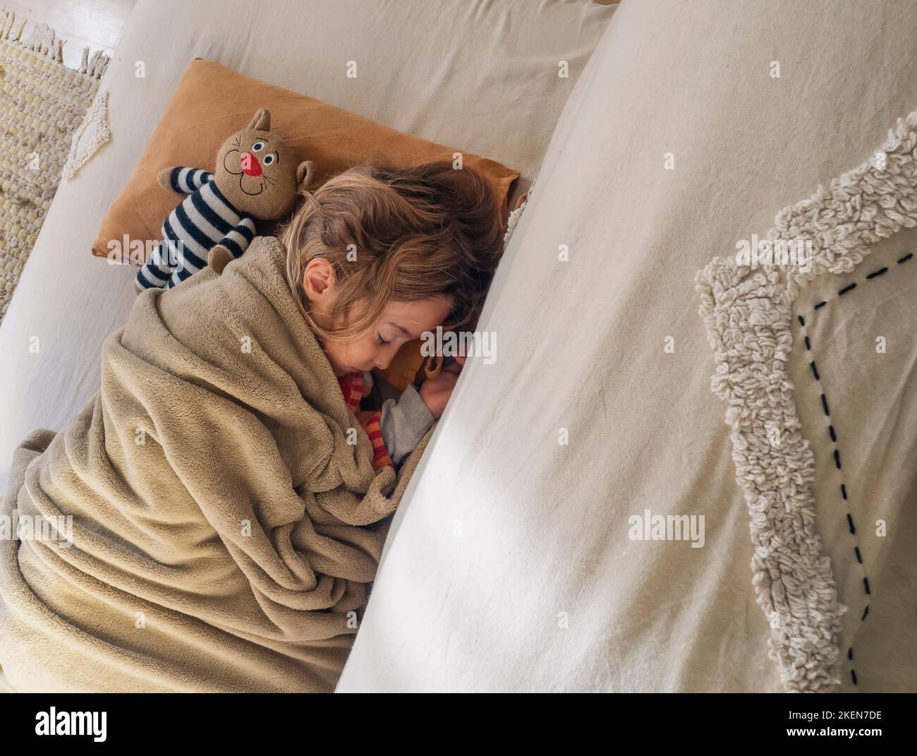 Adorabile bambina dorme sul divano accanto al suo animale farcito preferito Foto Stock