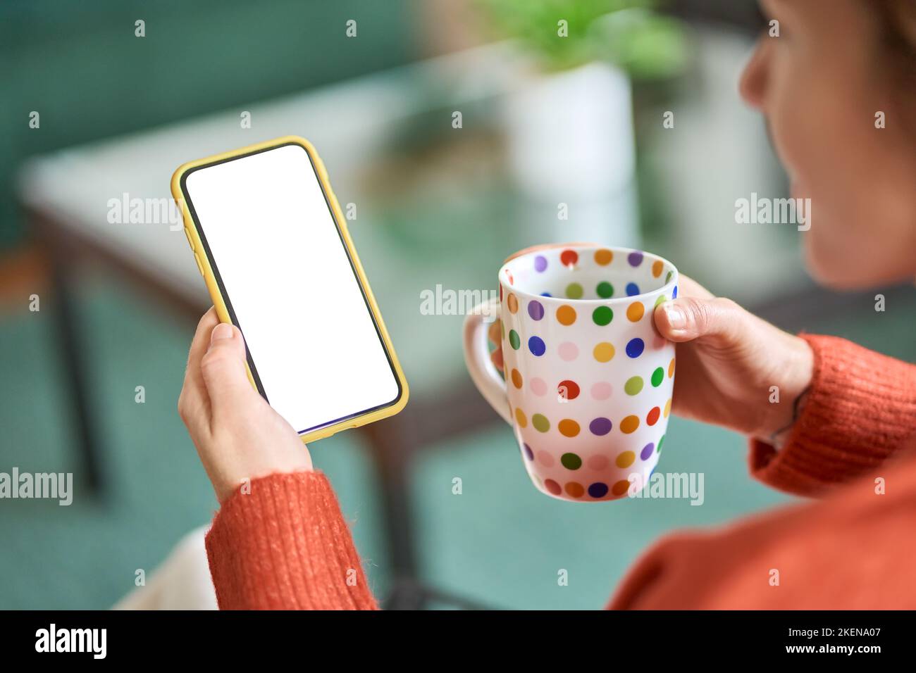 Donna che tiene lo smartphone bianco mock up schermo e caffè, a spalla. Foto Stock