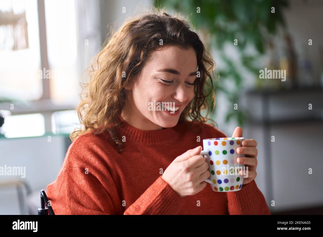 Giovane donna felice bella bere tè o caffè rilassante a casa. Foto Stock