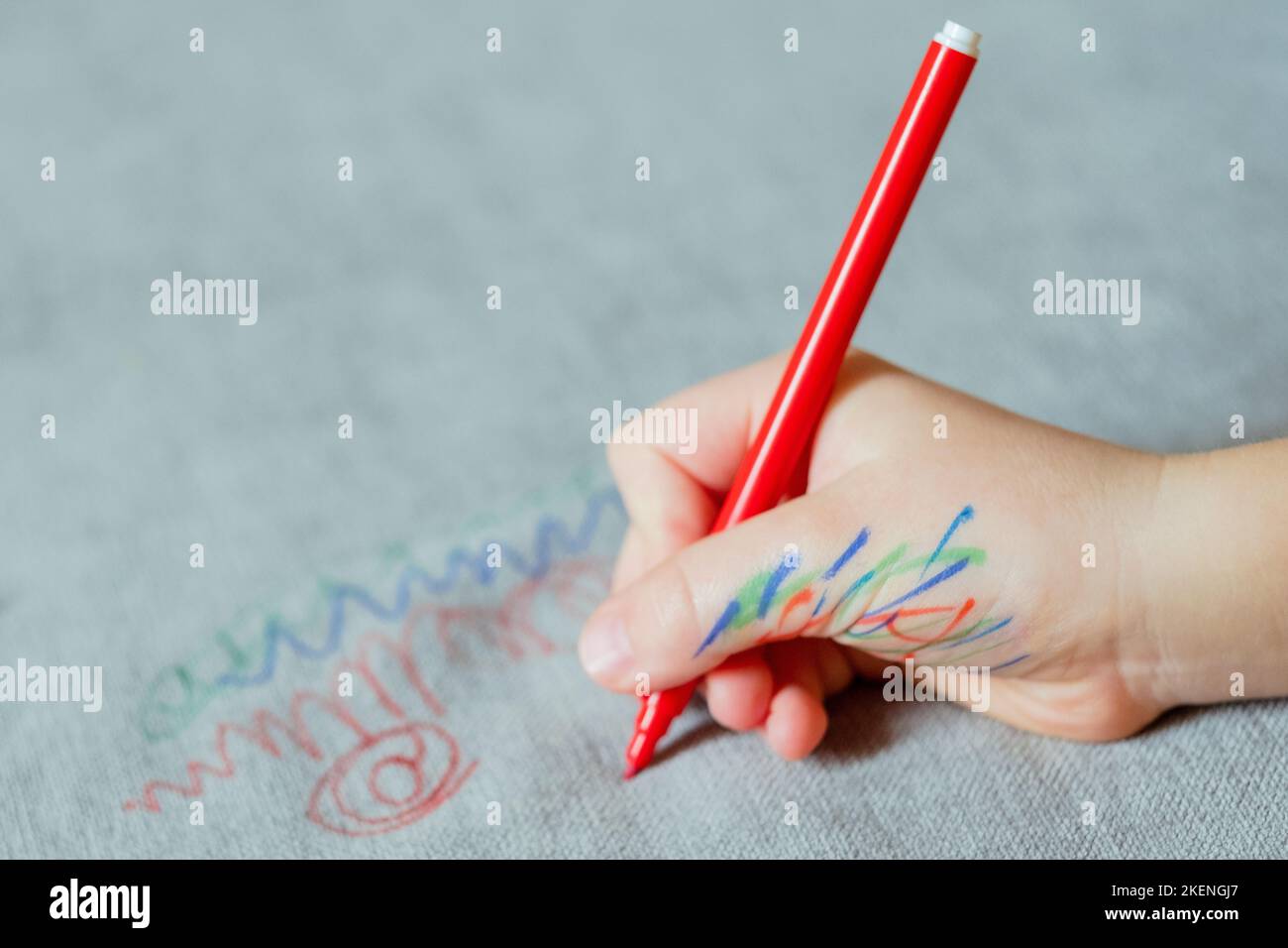 Un bambino si è macchiato di mano d'inchiostro, disegnando con un contrassegno rosso sul rivestimento del lettino. Tessuto per mobili. Concetto di pulizia Foto Stock