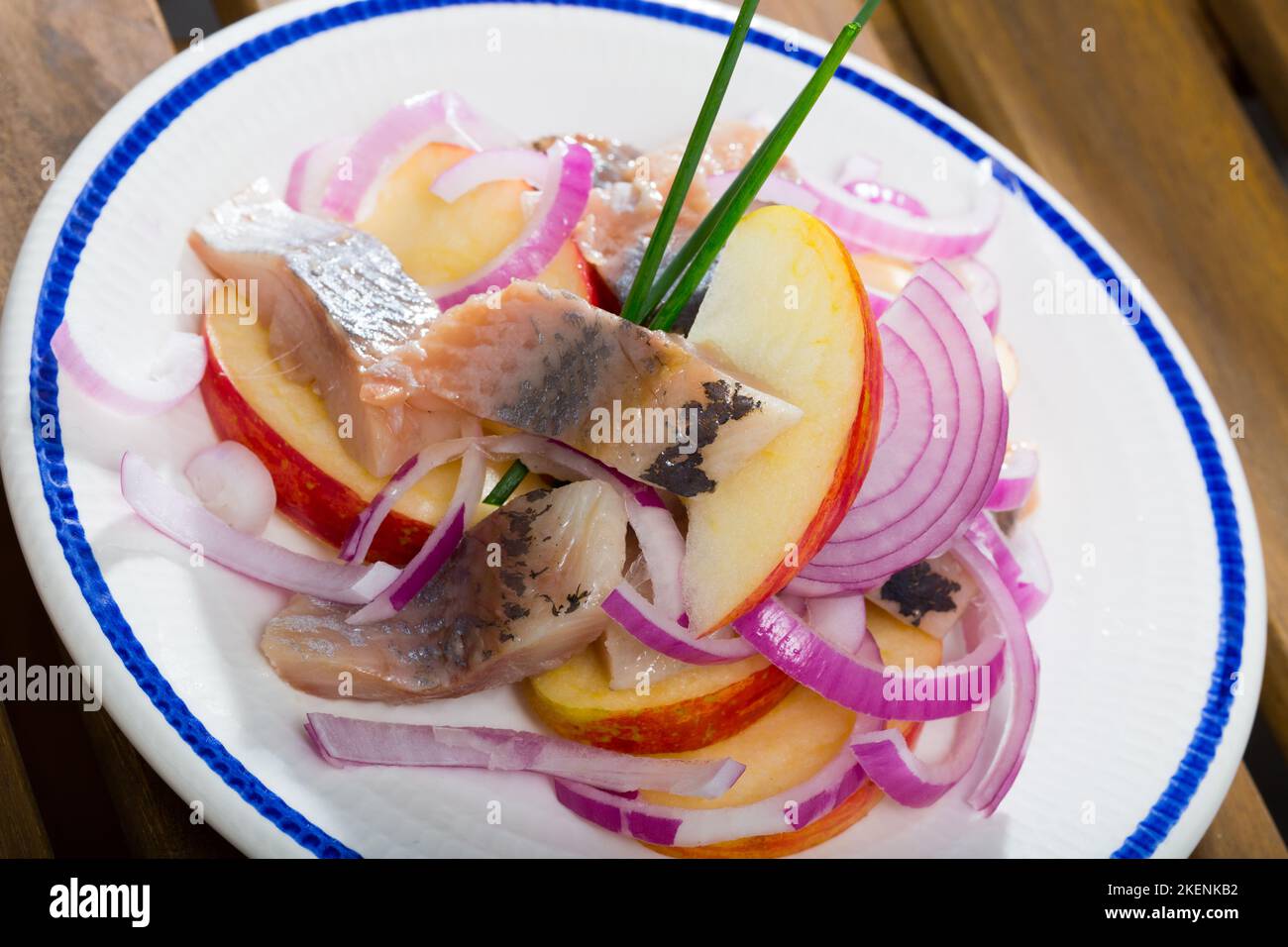 Patate fritte con fettine di aringhe mite e cipolle su piatto Foto Stock