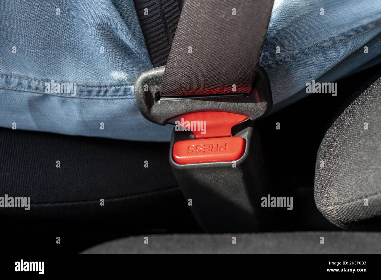 Primo piano della cintura di sicurezza con chiusura a bottoni rossi per sbloccare la cintura di sicurezza della vettura Foto Stock