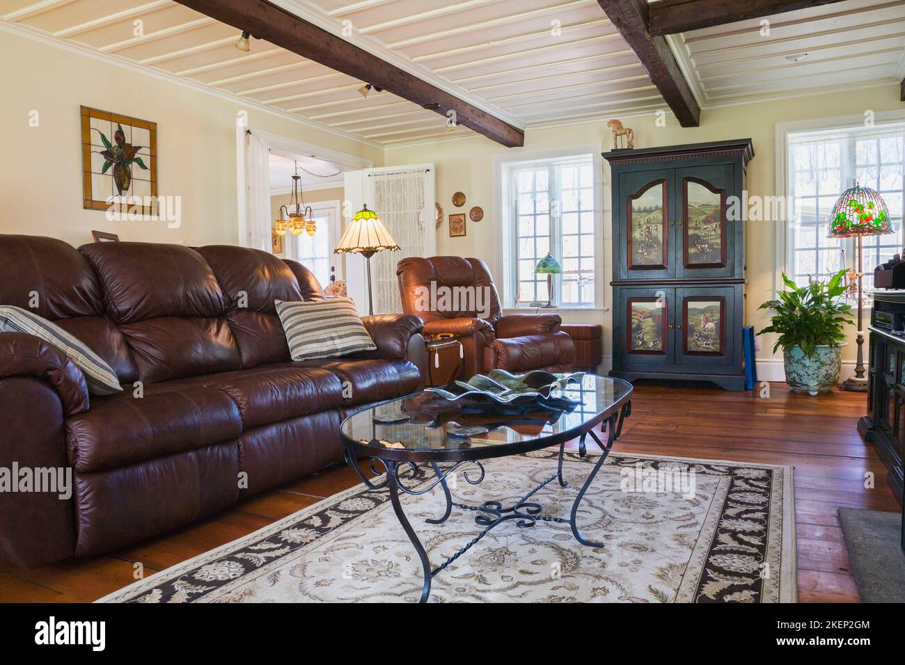 Divano in pelle marrone, poltrona e armadio in legno nel soggiorno all'interno di una vecchia casa in stile cottage canadese del 1886 ricostruita. Foto Stock