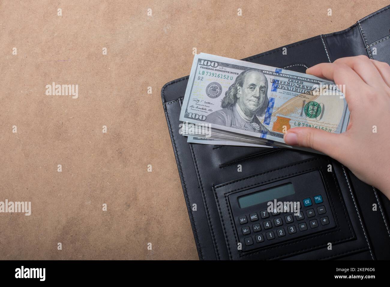 Mano che tiene le banconote del dollaro americano sulla calcolatrice Foto Stock