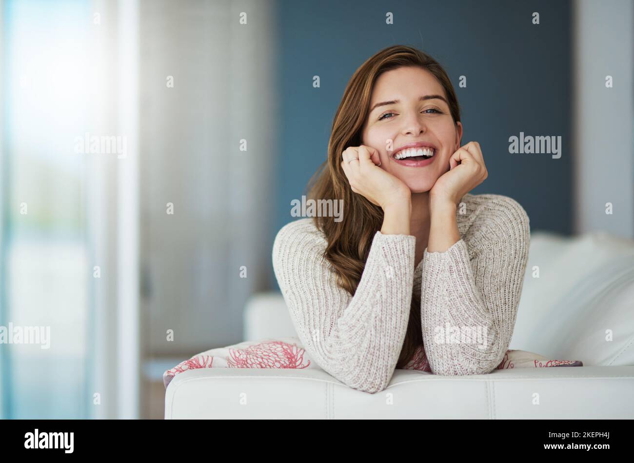 Rallenta e divertiti, una giovane donna che si rilassa sul divano di casa. Foto Stock