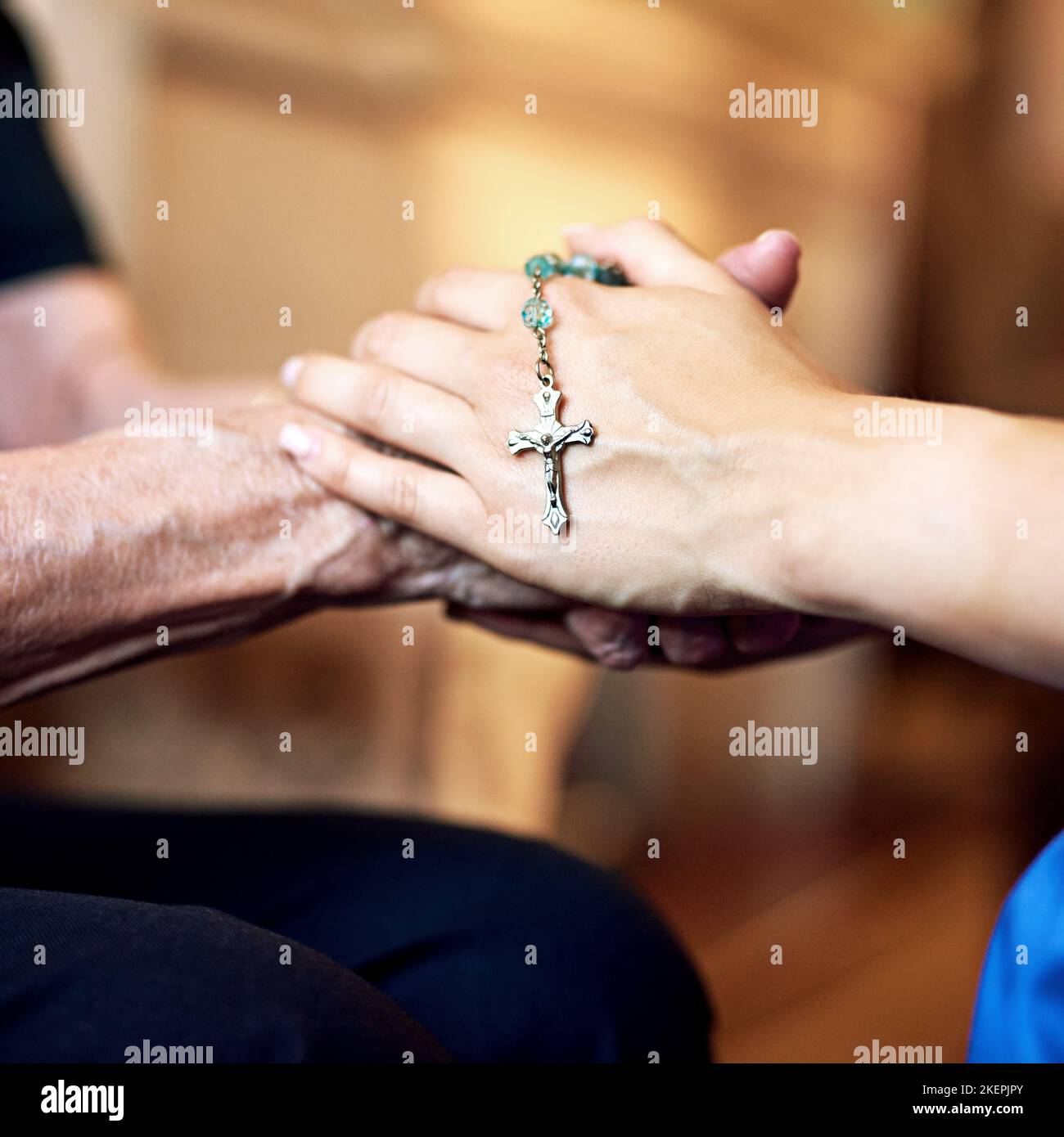 Uniti dalla fede: Una persona che tiene compassionatamente un rosario e una donna anziana. Foto Stock