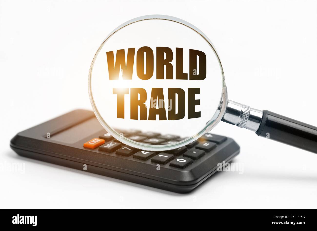 Concetto di business e finanza. Sulla tabella è riportata una calcolatrice e una lente d'ingrandimento, all'interno della quale è riportata l'iscrizione World Trade Foto Stock