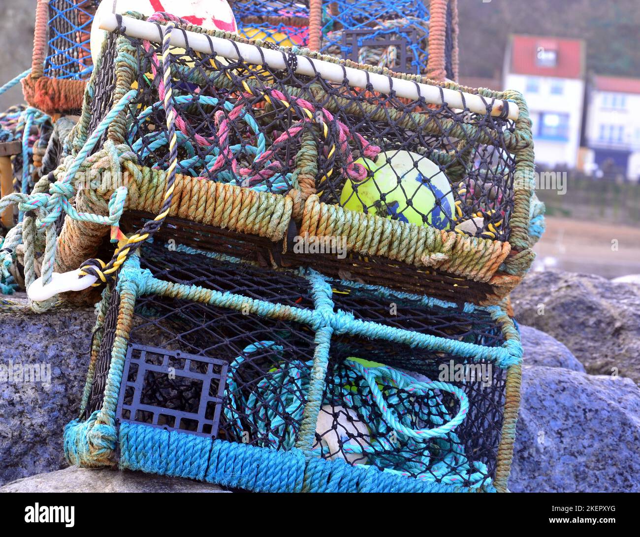 Vasi di pesca di granchio e aragosta impilati accanto al porto o con cottage sullo sfondo a Staithes, Yorkshire, Regno Unito. Foto Stock