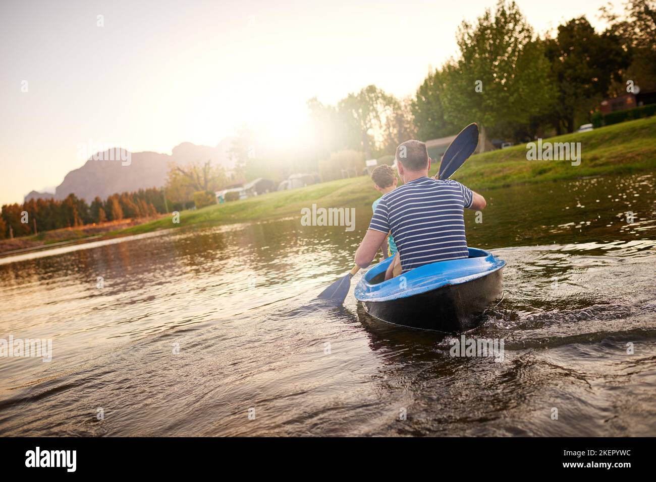 Un padre e un figlio che canottano una barca insieme su un lago. Foto Stock