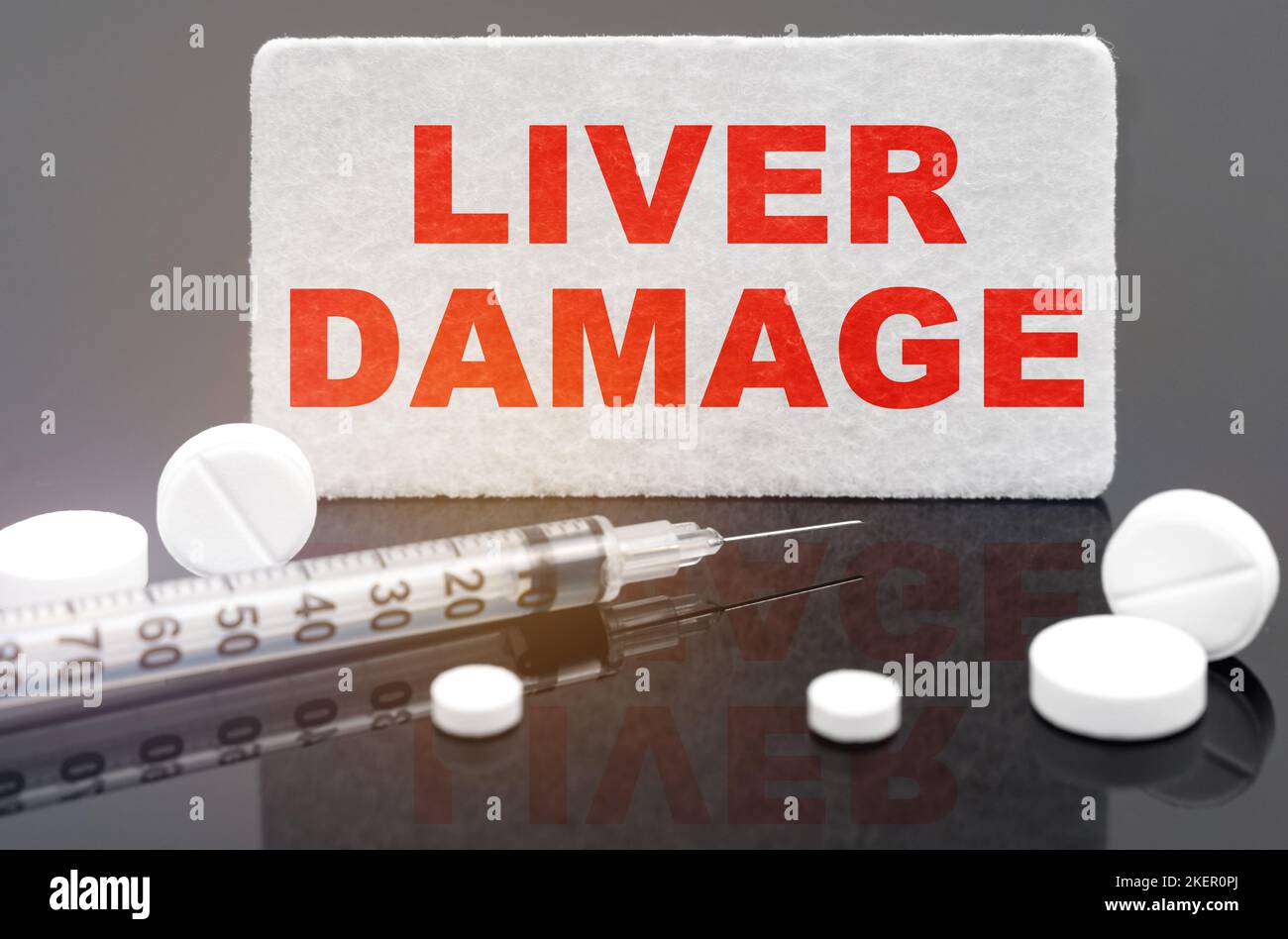 Medicina e concetto di salute. Su una superficie nera riflettente, pillole, una siringa e un segno con l'iscrizione - danno al fegato Foto Stock