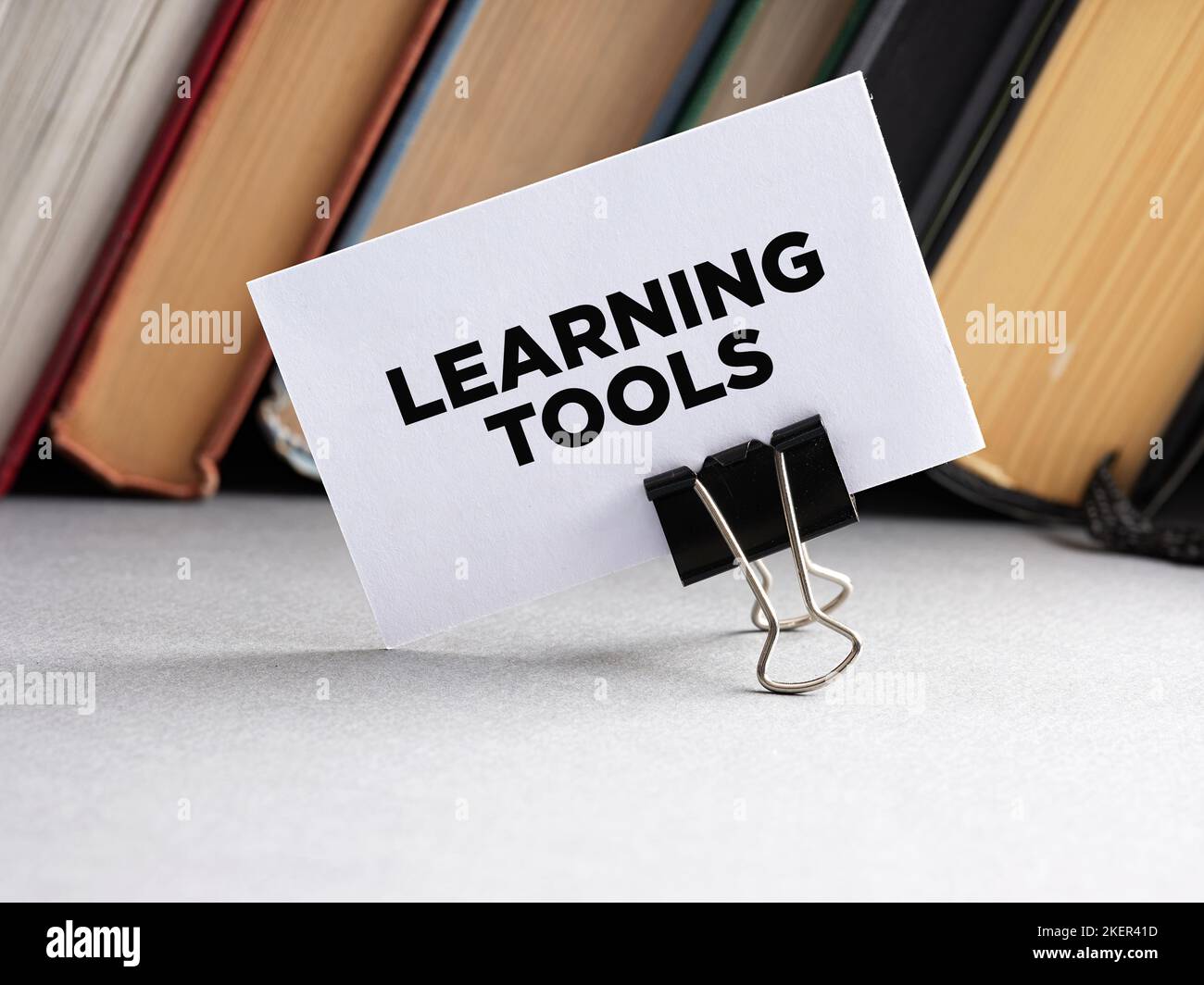Gli strumenti di apprendimento del messaggio scritti su un biglietto da visita con lo sfondo dei libri. Foto Stock