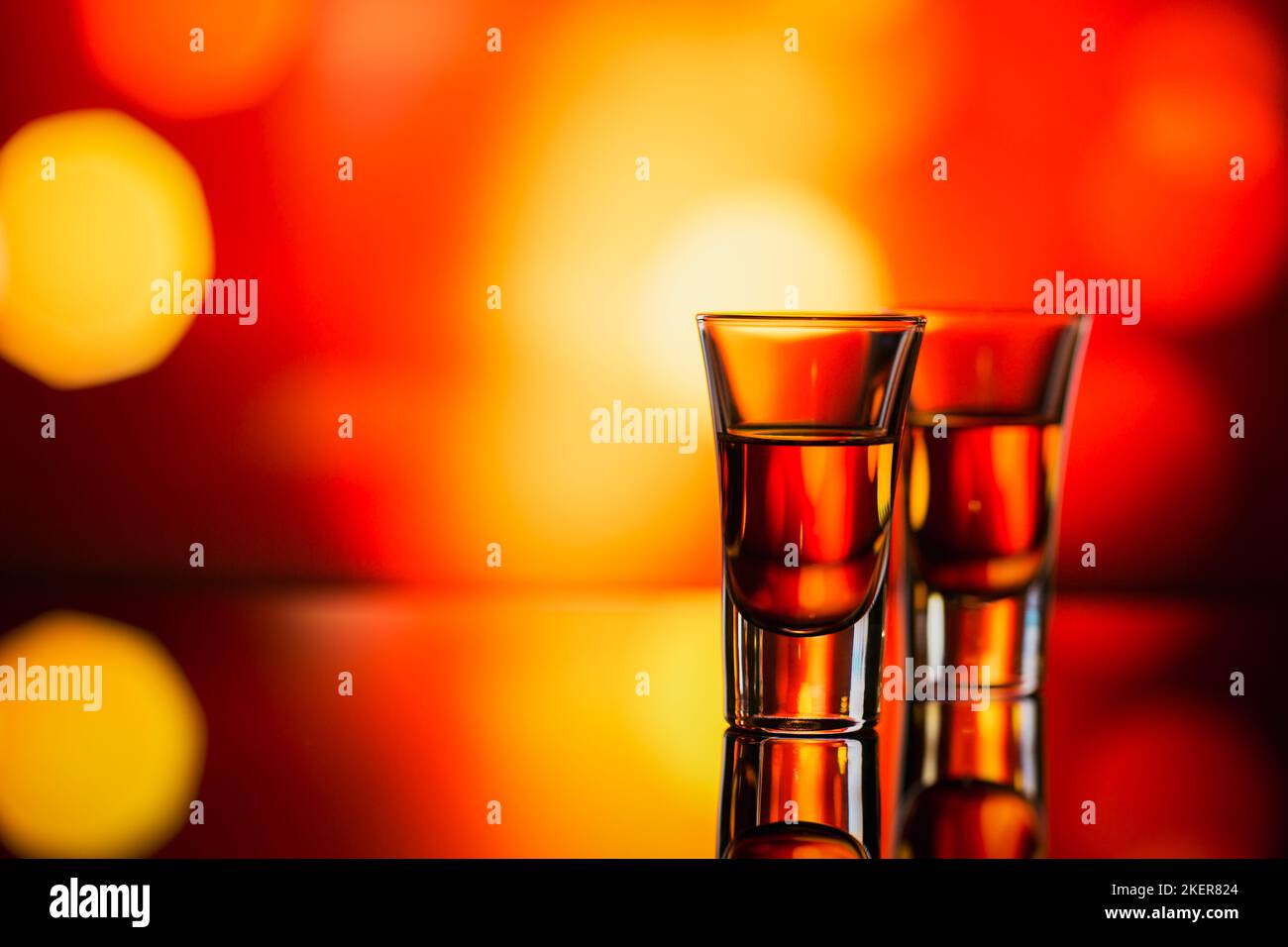 Due bicchieri di whisky o bourbon su sfondo bokeh rosso. Concetto di umore del whiskey Foto Stock