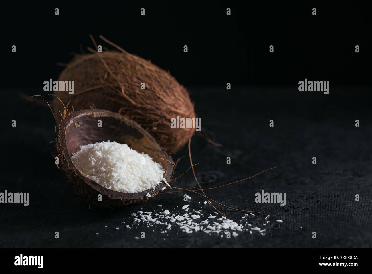 Cocco intero con scaglie di cocco su sfondo nero Foto Stock