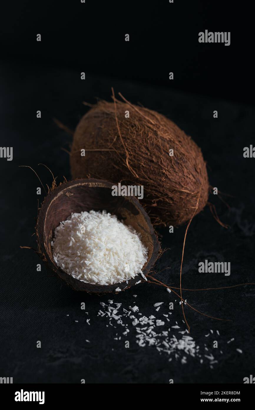 Cocco intero con scaglie di cocco su sfondo nero Foto Stock