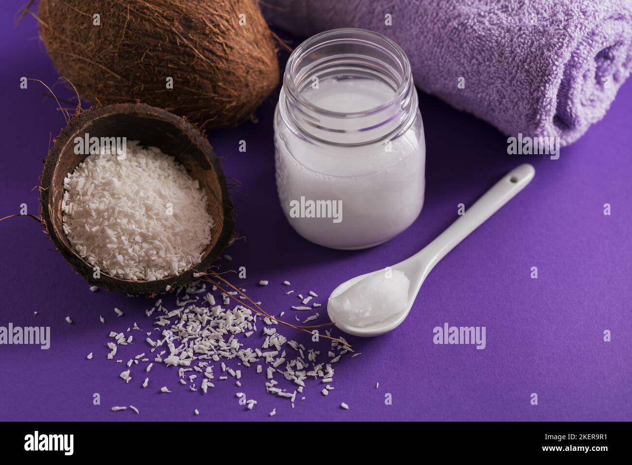 Composizione con crema corpo cosmetica naturale di olio di cocco organico su fondo di colore viola. Bellezza naturale e concetto di cura del corpo Foto Stock