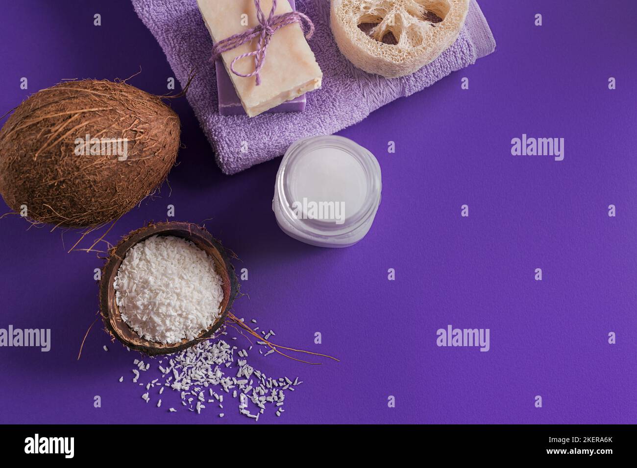 Composizione con crema corpo cosmetica naturale di olio di cocco organico su fondo di colore viola. Bellezza naturale e concetto di cura del corpo Foto Stock