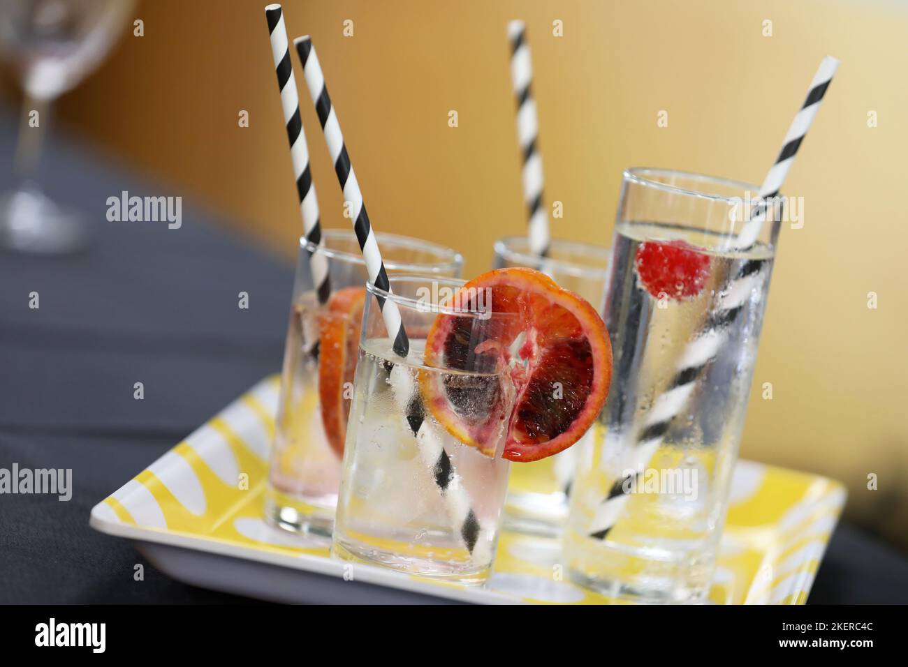 Un vassoio di diversi bicchieri da bibita riempiti di acqua ghiacciata e limpida o di soda guarnita con una fetta di sangue o di arancia rossa e ciliegie. Foto Stock