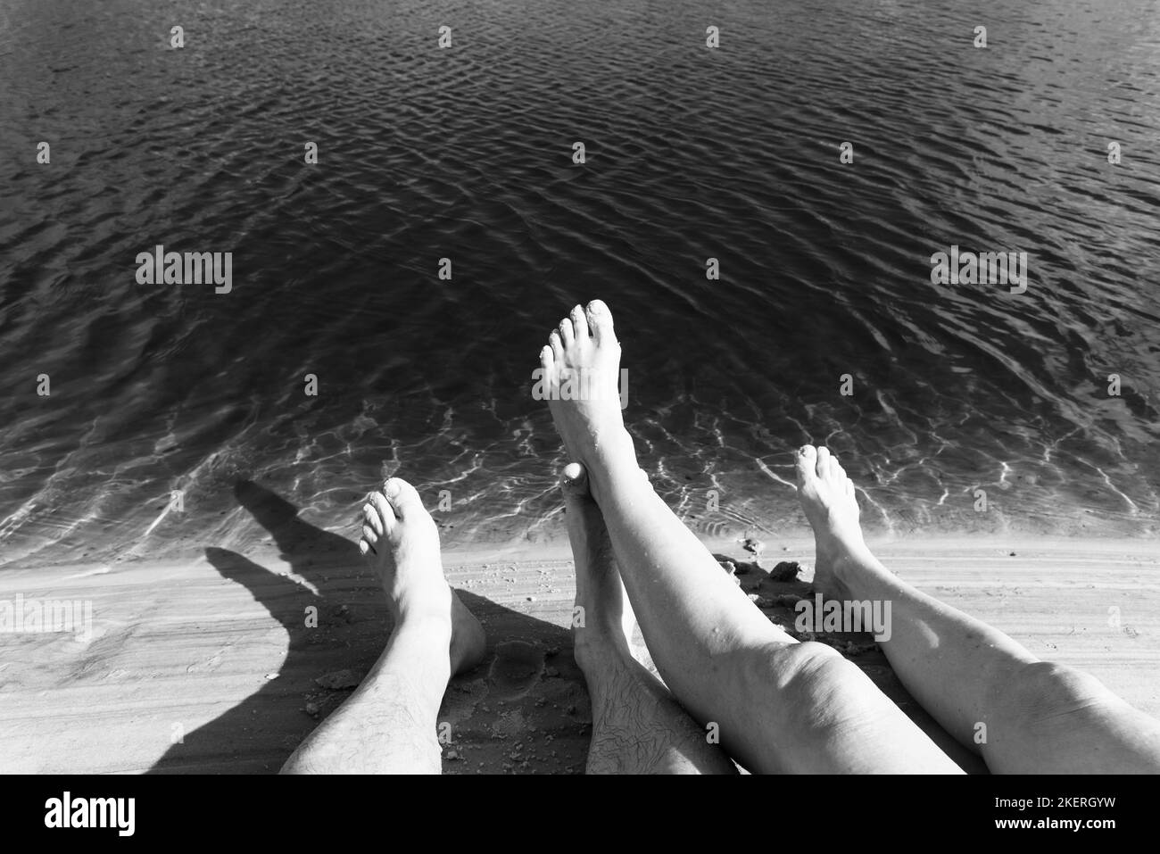 Gambe di un uomo e di una donna sul fiume contro l'acqua rossastra sullo sfondo. Guaibim spiaggia nella città di Valenca, Bahia, Brasile. Foto Stock