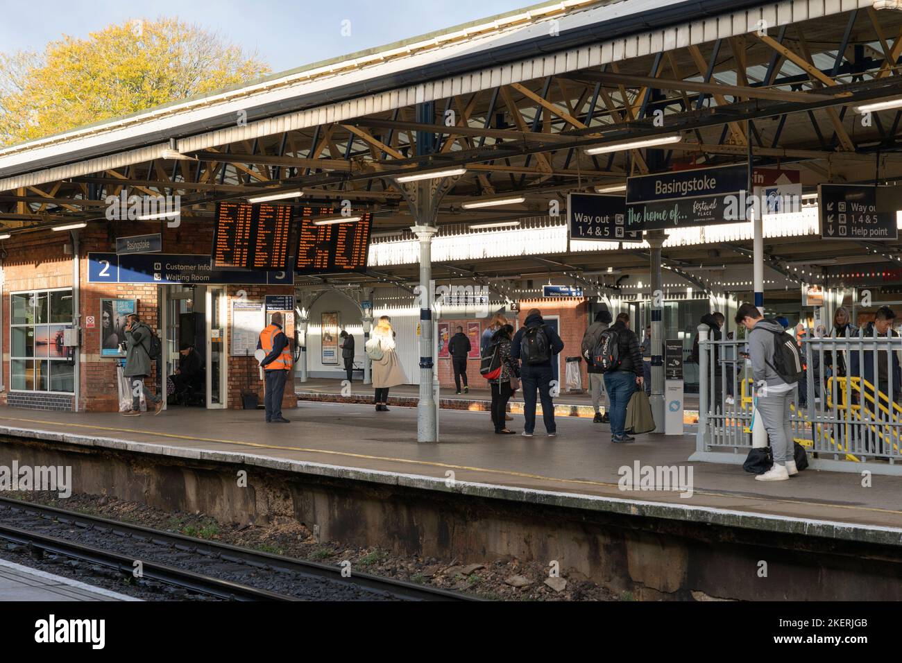 Pendolari in attesa di un binario per un treno alla stazione di Basingstoke in un giorno d'autunno. Hampshire, Inghilterra Foto Stock