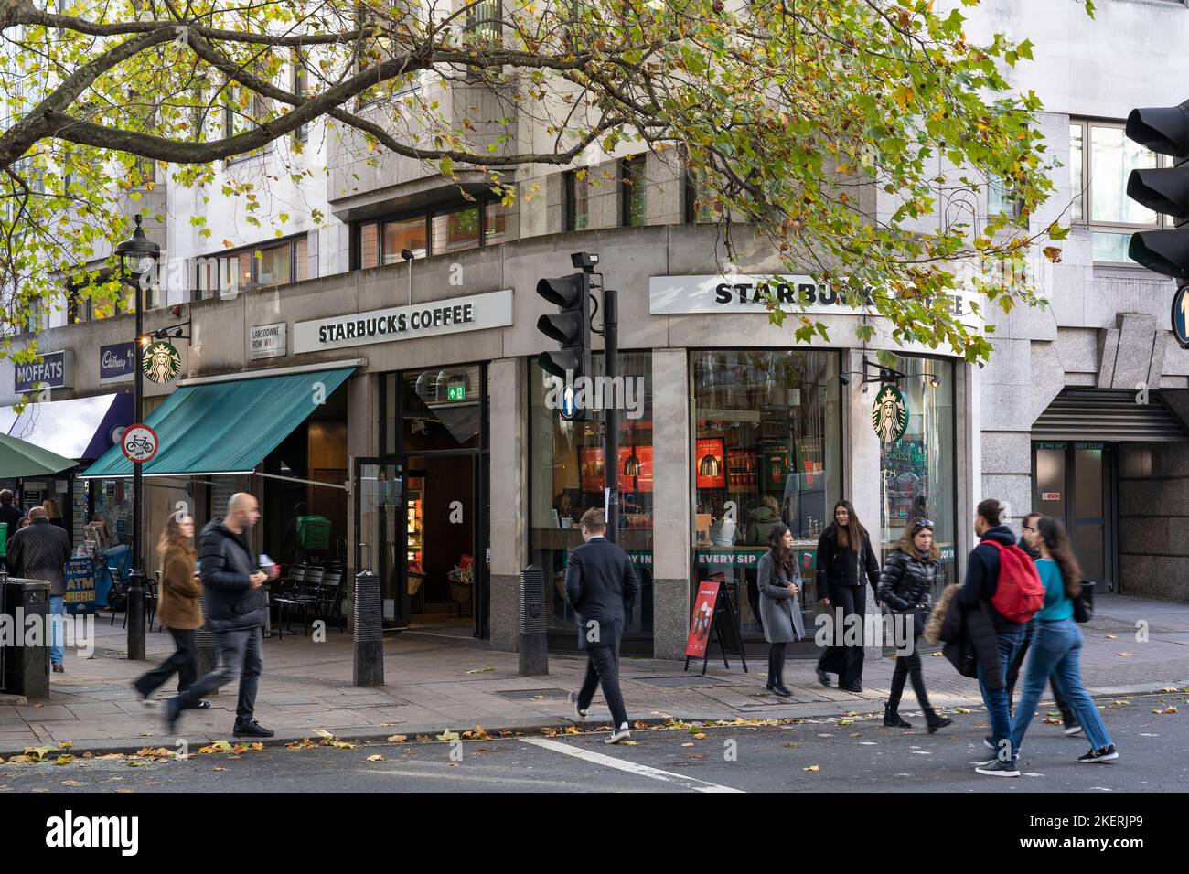 La gente passa davanti a uno Starbucks Coffee Shop a Lansdowne Row a Londra. Inghilterra. Tema: Cultura del caffè, la corsa dei topi, la più grande catena di caffetterie Foto Stock