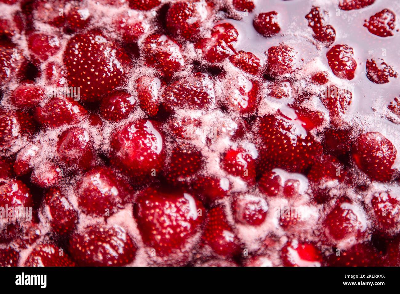 PRIMO PIANO: Marmellata di fragole. Fare una marmellata di fragole. Lessate le fragole nella padella. Processo di cottura, bacche bollenti per inscatolamento. Cibo dolce sano. Cottura della marmellata di fragole da vicino. Foto Stock