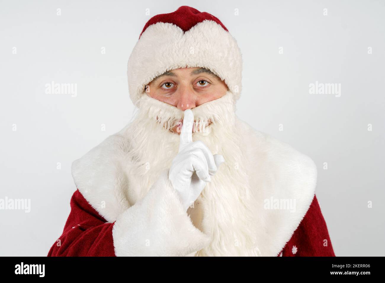 Concetto di Capodanno e Natale. Babbo Natale mise il dito sulle labbra. Mostra ciò che deve essere fatto tranquillamente. Sfondo isolato Foto Stock