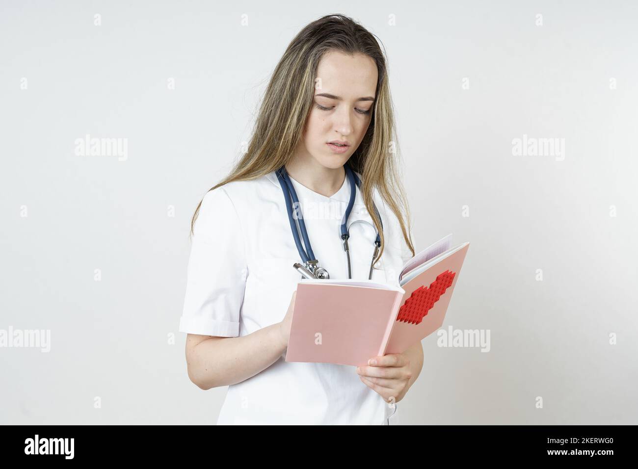 Medicina e concetto di salute. Una giovane dottoressa scrive in un taccuino. Isolato su bianco Foto Stock