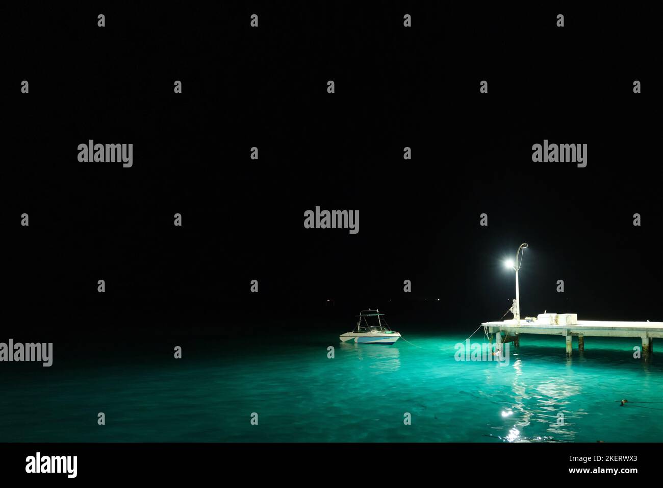 Una donna locale che pesca sul lato del molo durante la notte. Foto Stock