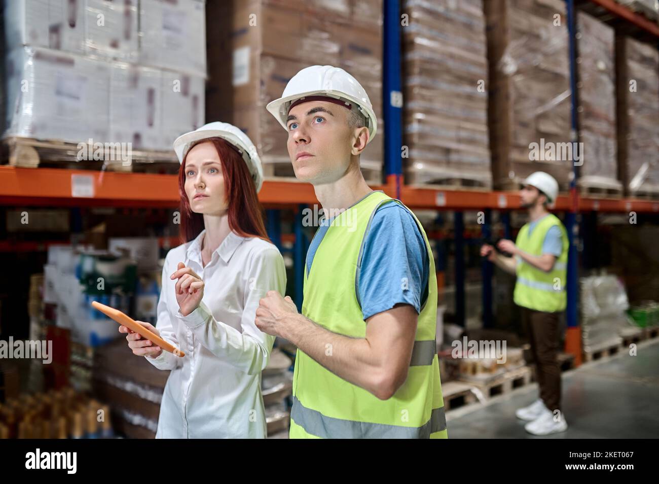 Team di dipendenti del magazzino che eseguono un'ispezione dell'impianto di scaffalatura Foto Stock