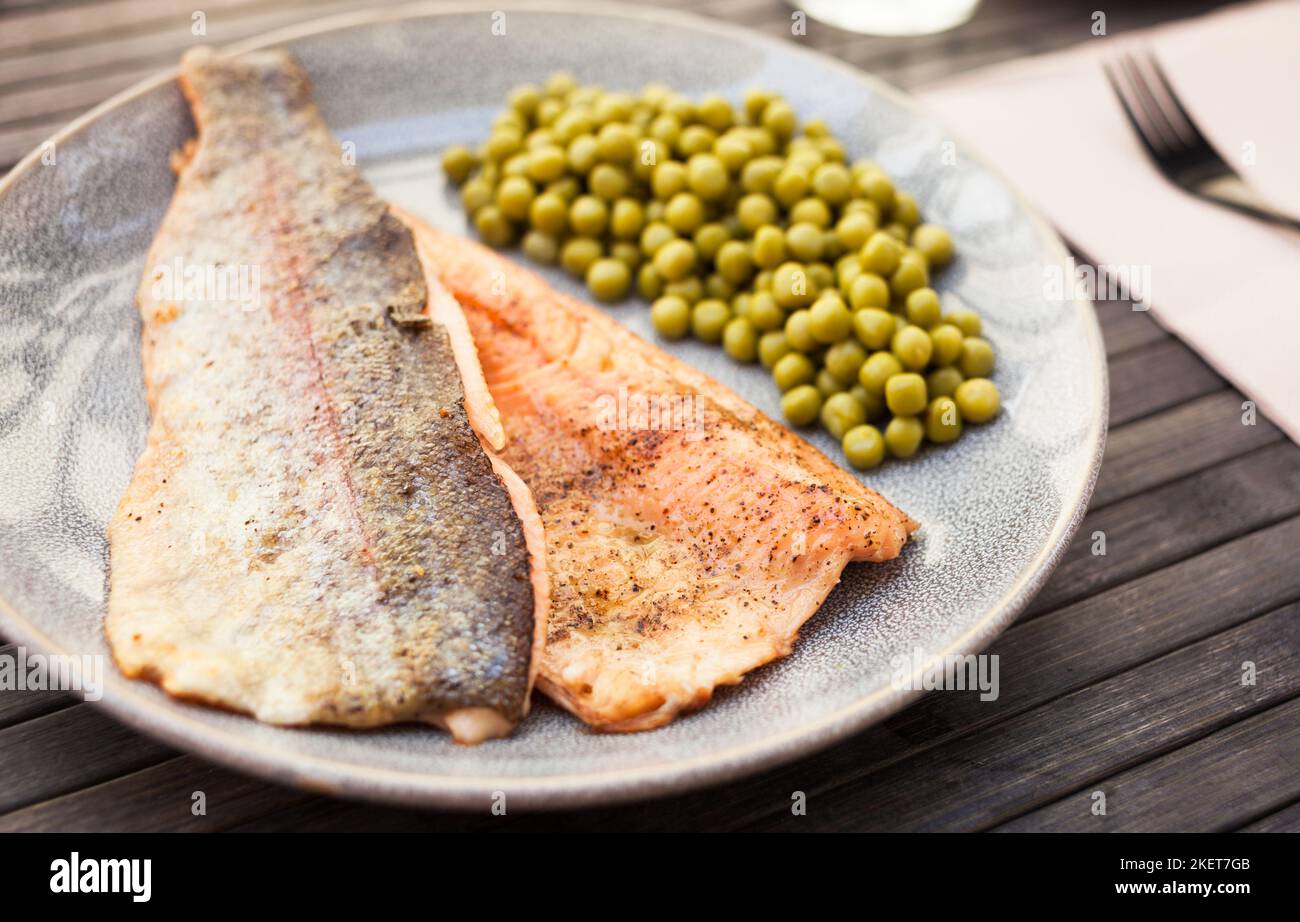 Filetti di trota fritti serviti con piselli verdi Foto Stock