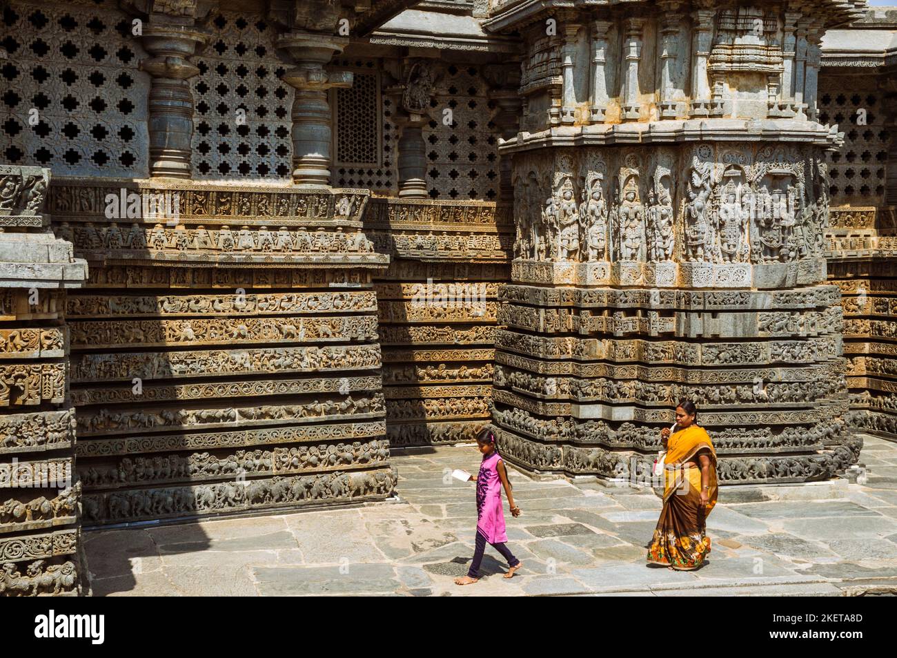Halebid, Karnataka, India : Una donna e una ragazza camminano intorno al Tempio Hoysaleswara del 12th ° secolo Foto Stock