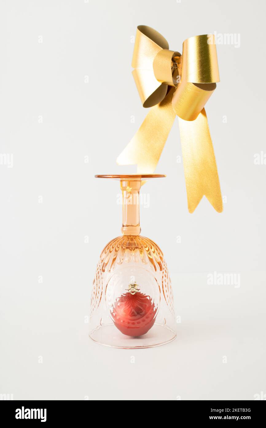 Natale in vetro da bere vintage e nastro dorato su sfondo bianco. Concetto di anno nuovo minimo. Foto Stock