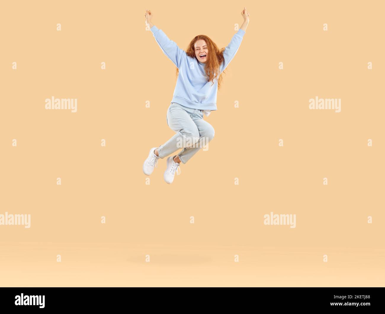 Felice giovane donna gioiosa in abiti casual sta avendo divertimento e saltando sul trampolino Foto Stock
