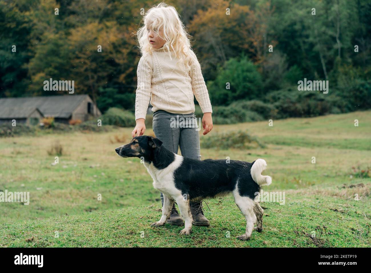 Bambina che cammina nel villaggio con il suo cane. Foto Stock