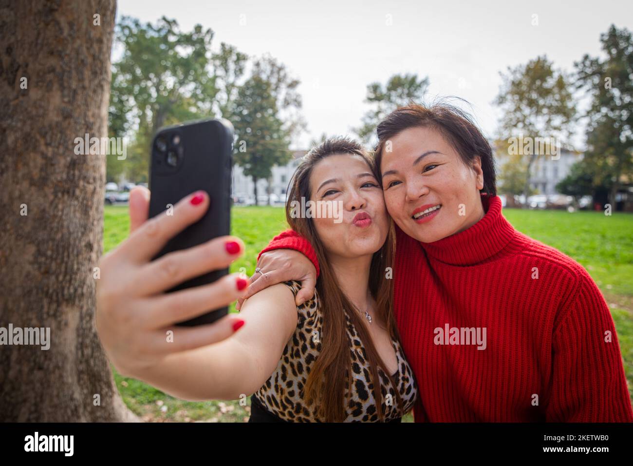 Due amici asiatici prendono un selfie in un parco all'aperto, buone donne cinesi mature Foto Stock