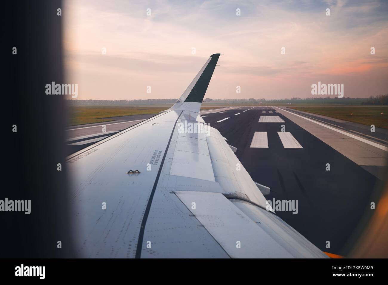 Vista dalla finestra dell'aereo all'aeroporto al tramonto. Aereo durante la tassazione alla pista prima del decollo. Foto Stock