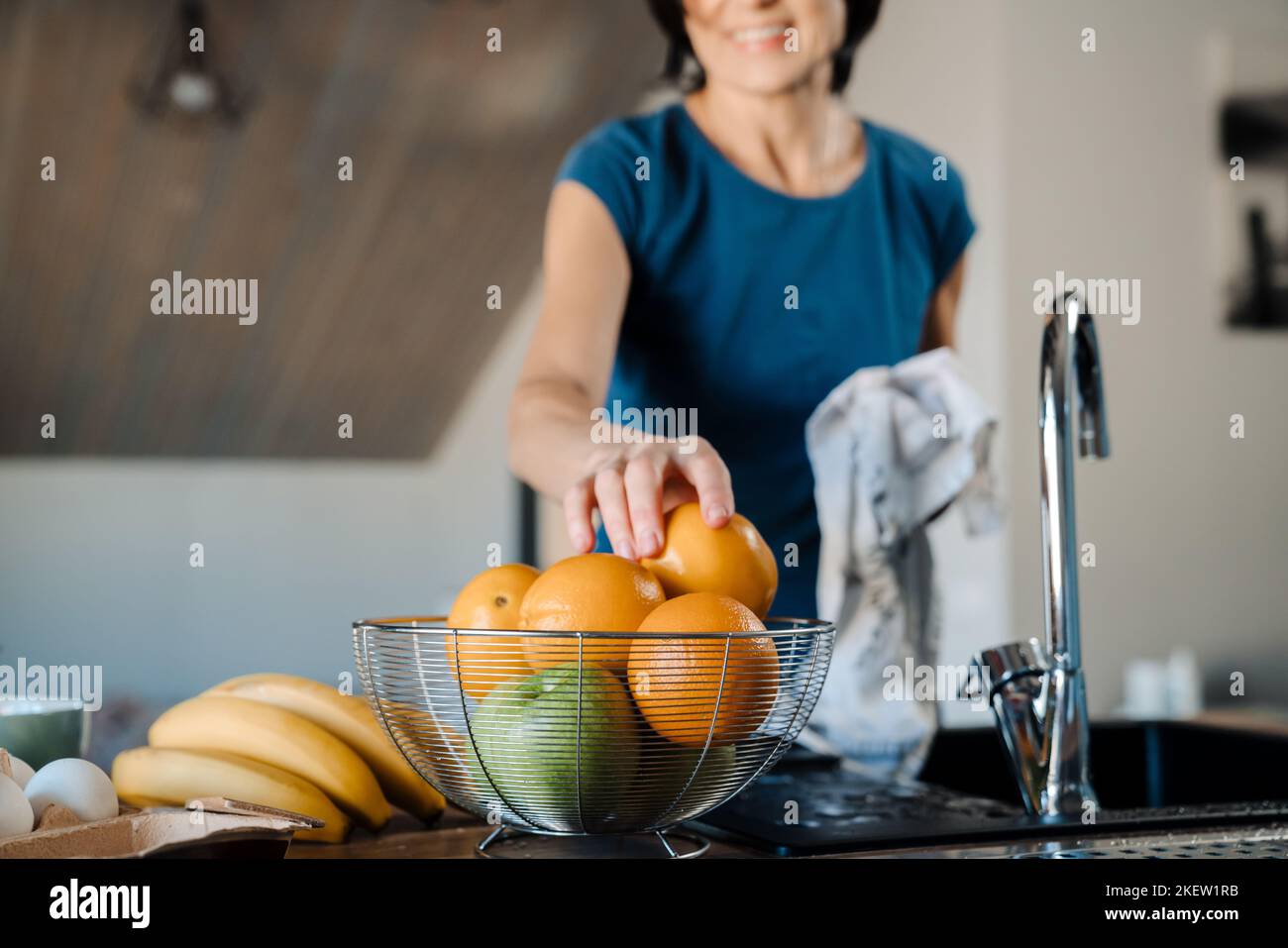 Donna matura bianca che asciuga la frutta mentre cucinava in cucina a casa Foto Stock