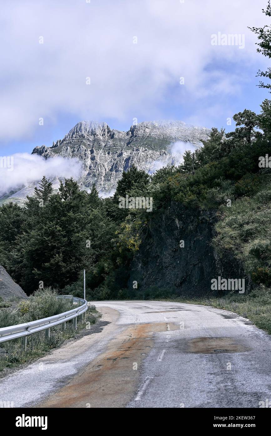 strada sterrata stretta attraverso la foresta accanto agli alberi in direzione delle imponenti montagne rocciose, ruta del cares asturias, spagna Foto Stock