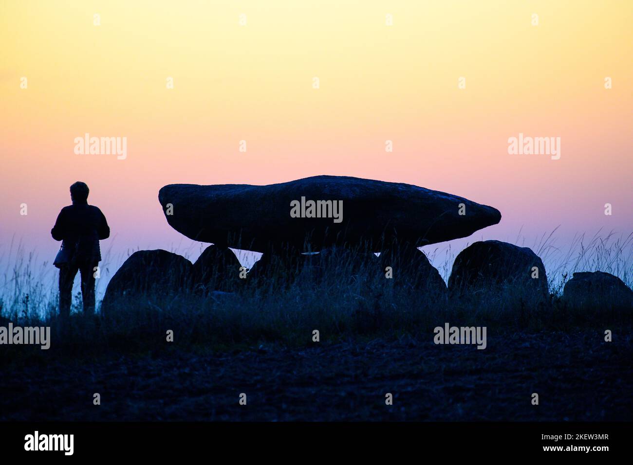 Drosa, Germania. 14th Nov 2022. Dopo il tramonto, un camminatore si trova presso la tomba megalitica di Drosa. La tomba, chiamata 'Cantina del Diavolo', si dice risalga al periodo neolitico, che durò dal 4500 al 2000 a.C., secondo una bacheca informativa. Il tempo dovrebbe cambiare durante la settimana. Diventerà più instabile e il sole apparirà raramente. Credit: Klaus-Dietmar Gabbert/dpa/Alamy Live News Foto Stock