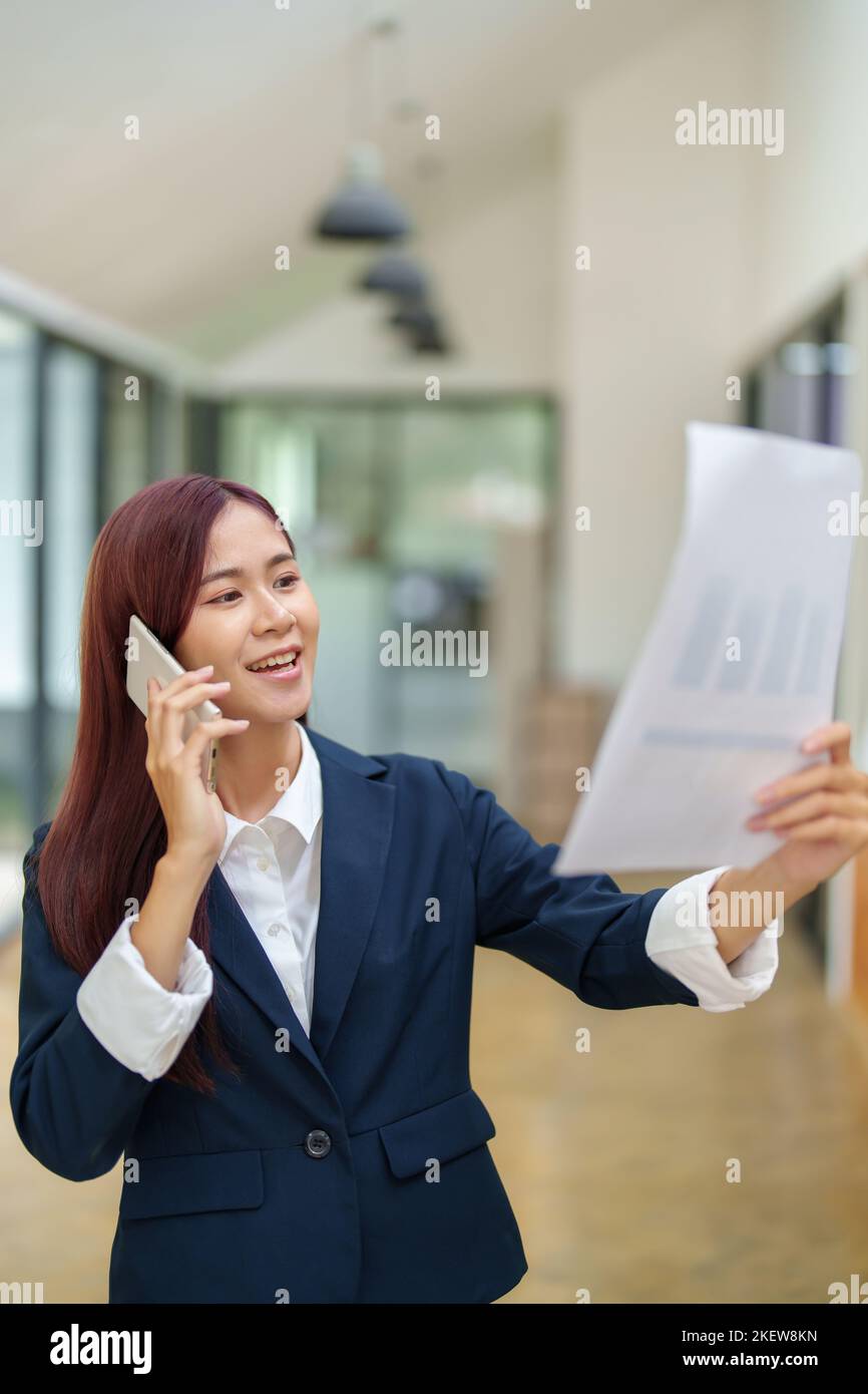 Donna d'affari asiatica che utilizza il telefono per contattare un partner commerciale Foto Stock