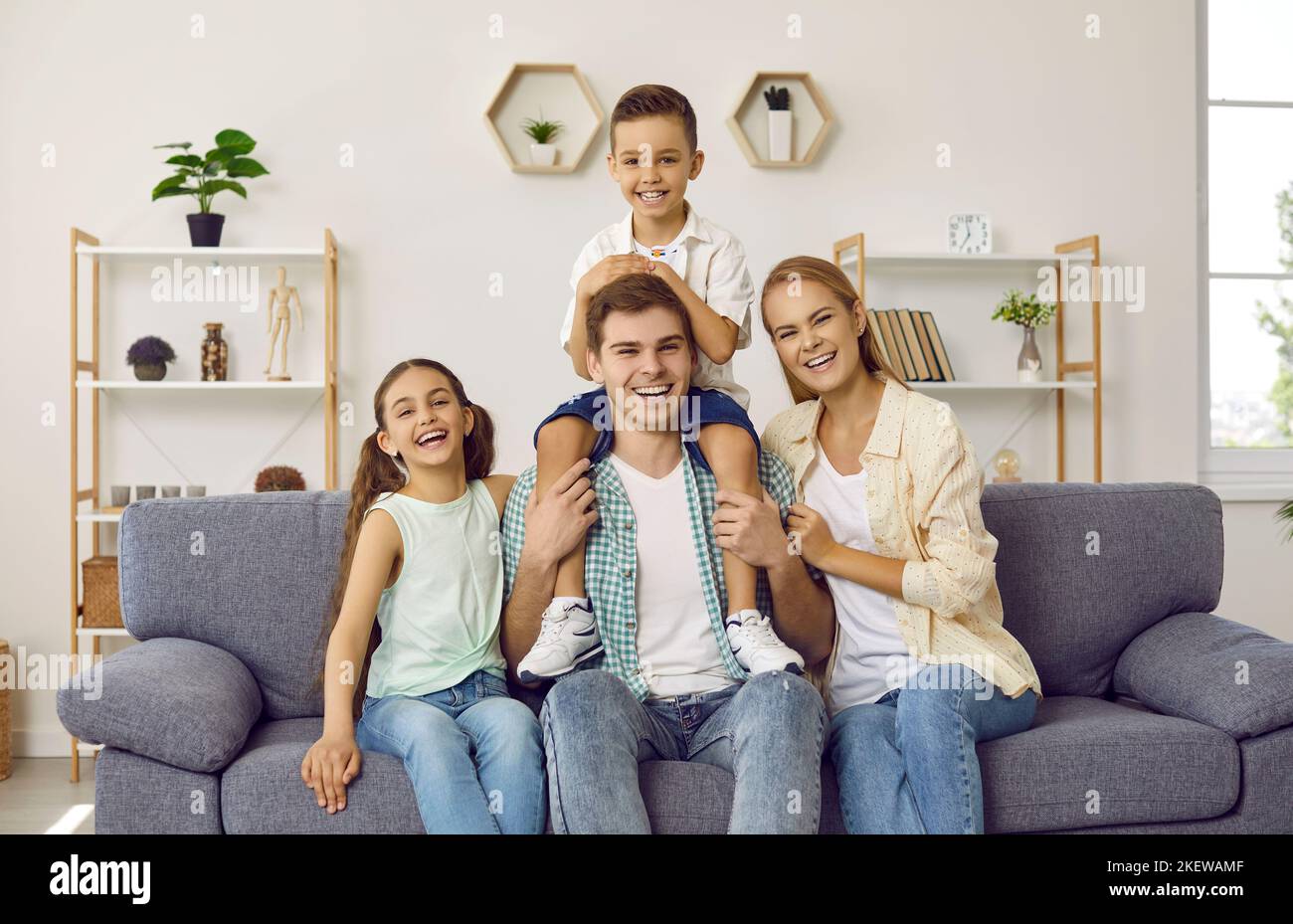 Ritratto di famiglia felice, allegra, ridente seduto sul divano di casa Foto Stock