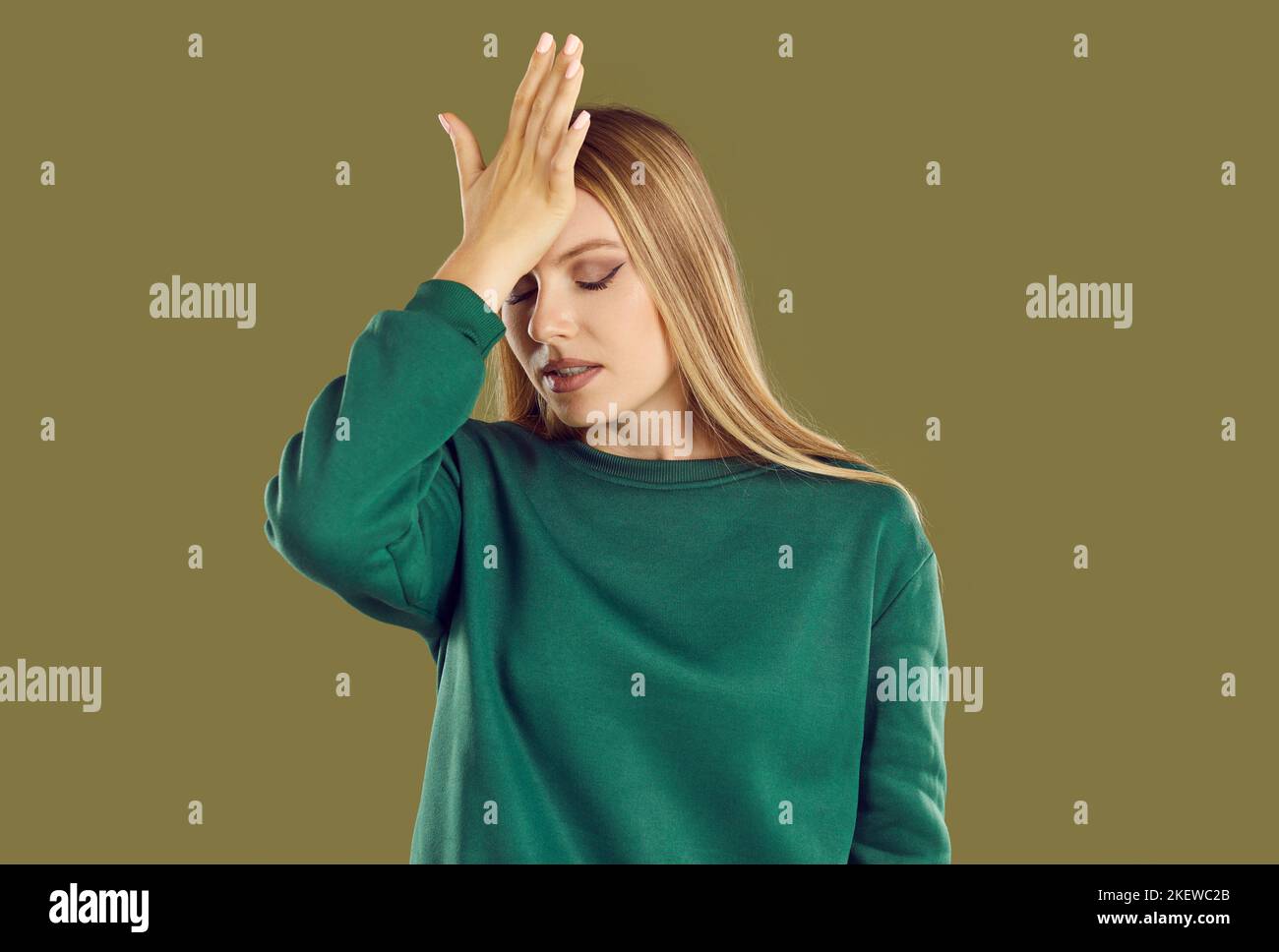 Una giovane donna dimentica si tocca la fronte con la mano, ricordando qualcosa di troppo tardi. Foto Stock