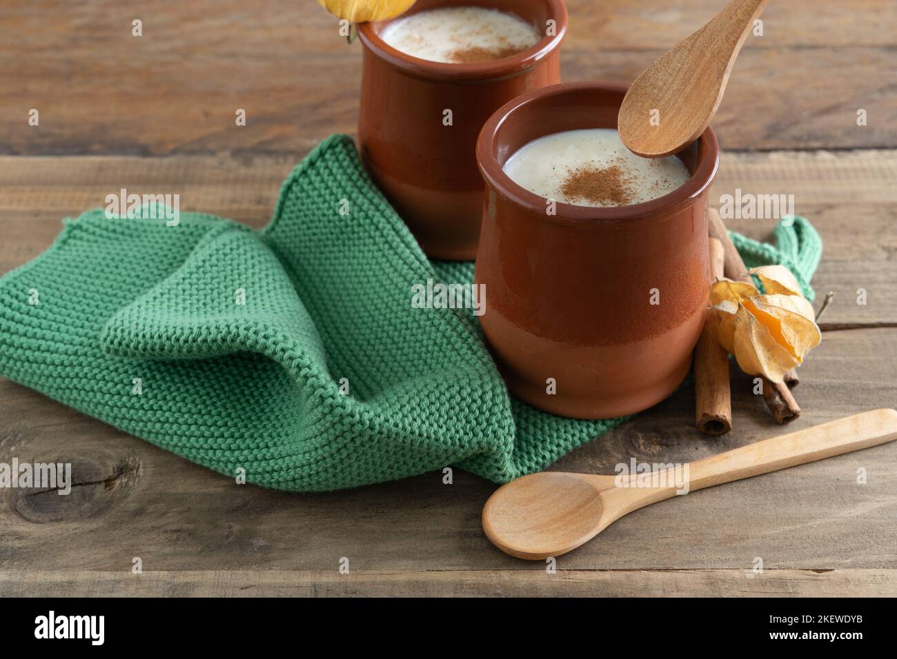 Ciotole in ceramica di budino di riso e cannella con decorazione su fondo in legno con cucchiai e straccio di tovagliolo. Spazio di copia. Foto Stock