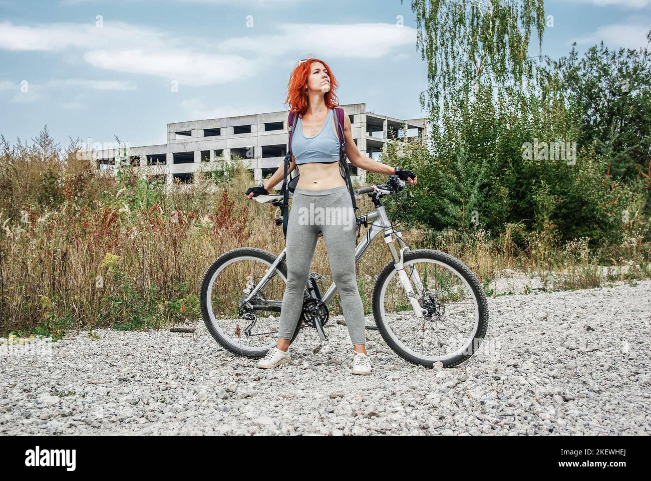 Ragazza in bicicletta sullo sfondo di una fabbrica abbandonata Foto Stock