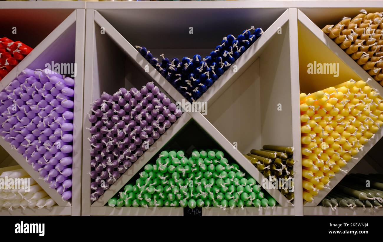 Candele colorate a bastoncino disposte su scaffali e ordinate per colore in un negozio di candele. Foto Stock